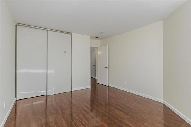 unfurnished bedroom featuring a closet and dark hardwood / wood-style flooring