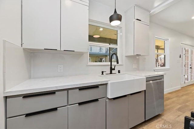 kitchen with white cabinetry, light stone counters, stainless steel dishwasher, pendant lighting, and light wood-type flooring