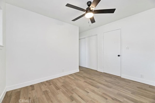 unfurnished bedroom featuring light hardwood / wood-style floors, ceiling fan, and multiple closets