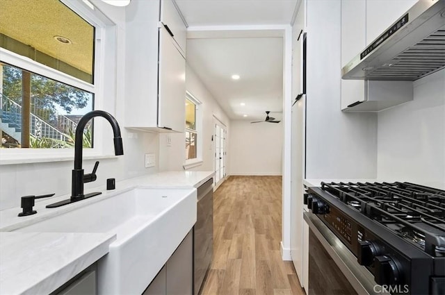 kitchen featuring white cabinets, sink, wall chimney range hood, and stainless steel appliances