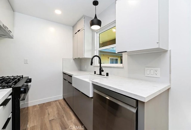 kitchen featuring light wood-type flooring, stainless steel dishwasher, black gas range oven, pendant lighting, and white cabinetry