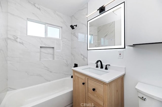 full bathroom featuring vanity, tiled shower / bath combo, and toilet