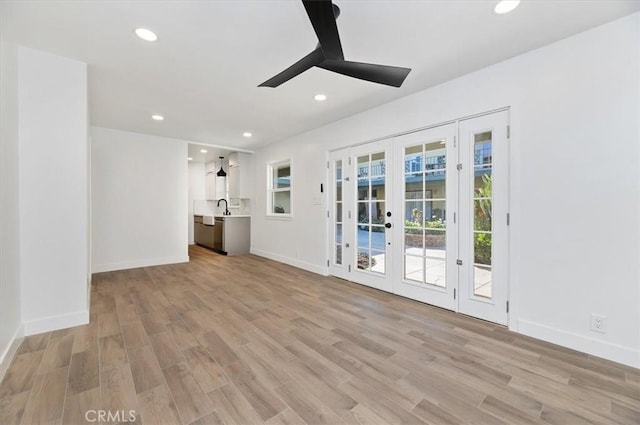 unfurnished living room with ceiling fan, light hardwood / wood-style floors, sink, and french doors