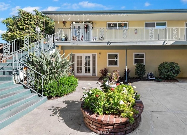 rear view of property with a patio area, a balcony, and french doors