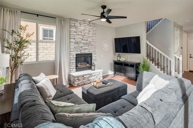 living room featuring a stone fireplace, ceiling fan, and hardwood / wood-style floors