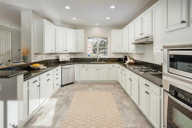 kitchen with dark stone counters, white cabinets, sink, appliances with stainless steel finishes, and light tile patterned flooring