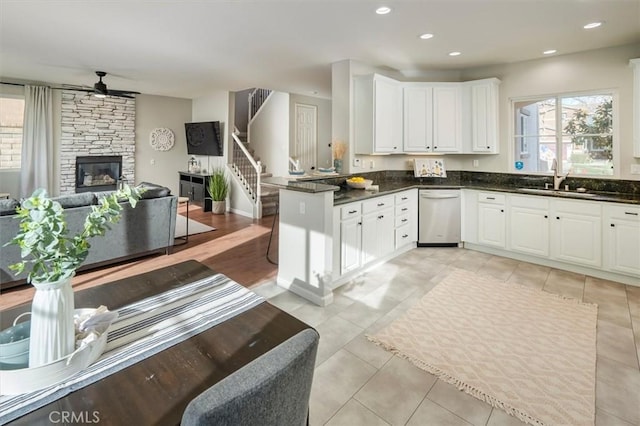 kitchen with white cabinetry, ceiling fan, sink, kitchen peninsula, and a fireplace