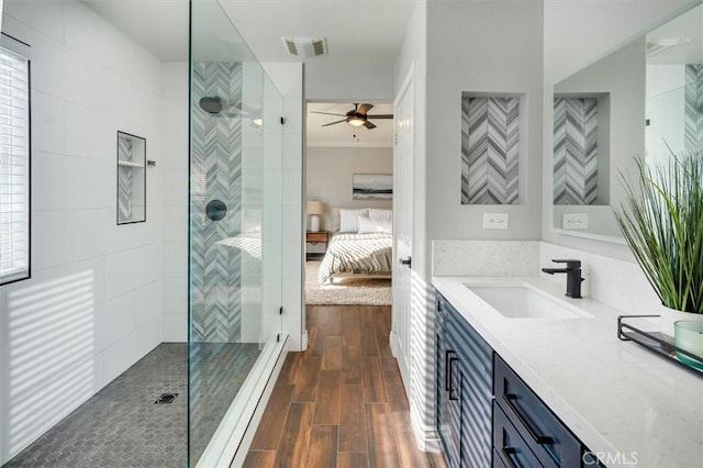 bathroom with ceiling fan, vanity, wood-type flooring, and tiled shower