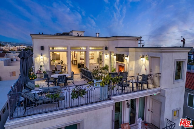 back house at dusk with a patio area and a balcony