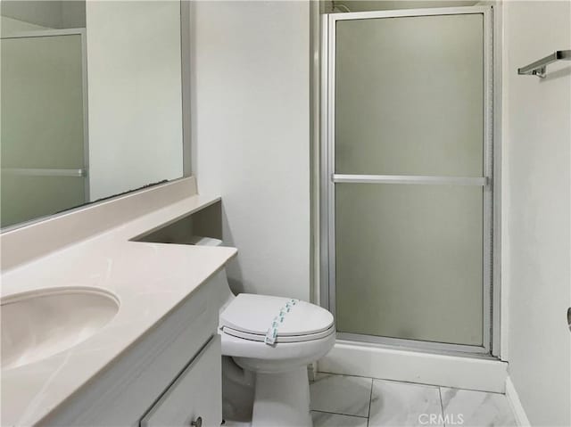 bathroom featuring toilet, vanity, and a shower with door