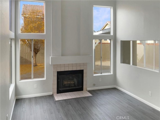 unfurnished living room featuring dark hardwood / wood-style floors and a tile fireplace