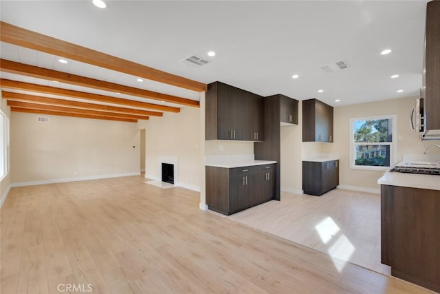 kitchen with beamed ceiling, dark brown cabinets, and light hardwood / wood-style flooring