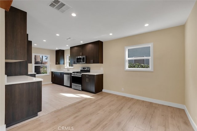 kitchen featuring light wood-type flooring, stainless steel appliances, dark brown cabinetry, and sink