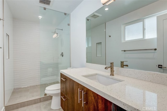 bathroom with tiled shower, vanity, toilet, and tile patterned flooring