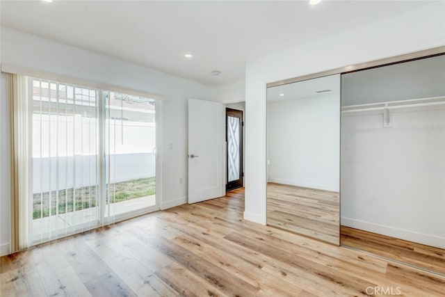 unfurnished bedroom featuring light hardwood / wood-style floors, access to exterior, and a closet