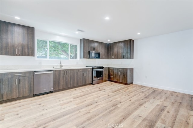 kitchen with dark brown cabinets, light wood-type flooring, sink, and appliances with stainless steel finishes