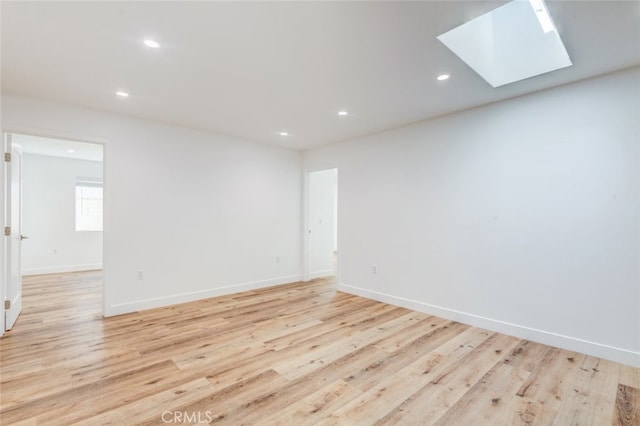 empty room featuring light hardwood / wood-style flooring and a skylight