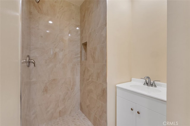 bathroom with a tile shower and vanity