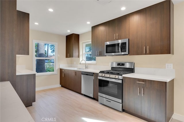 kitchen with sink, light wood-type flooring, and appliances with stainless steel finishes