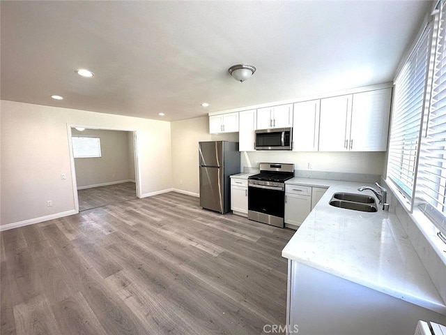 kitchen with white cabinetry, sink, light wood-type flooring, and appliances with stainless steel finishes