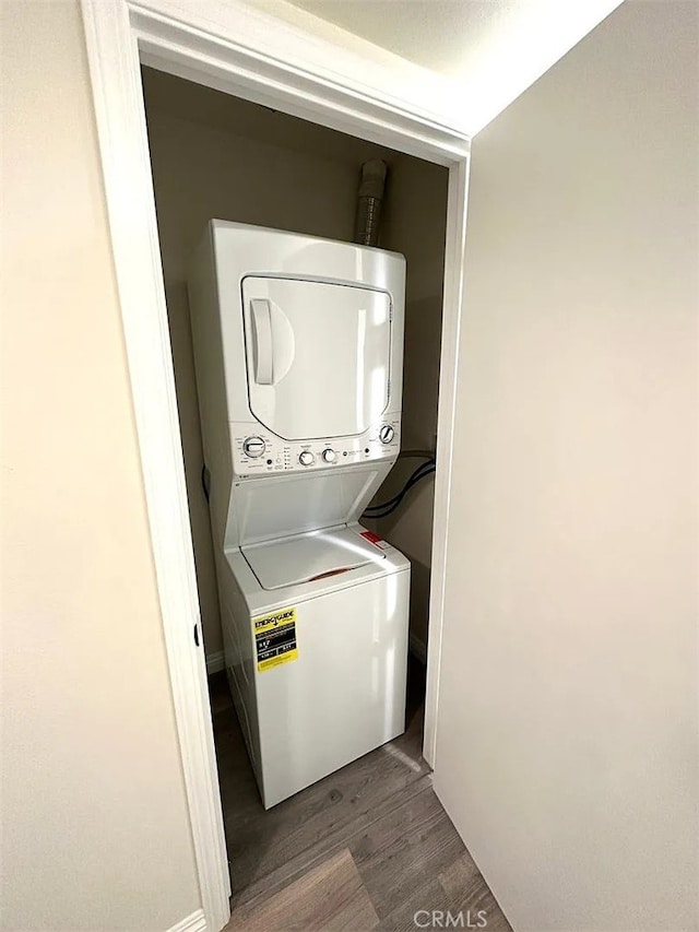 laundry area with hardwood / wood-style flooring and stacked washer / dryer