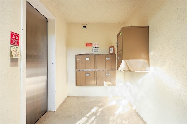 hall with elevator, mail boxes, and a textured ceiling