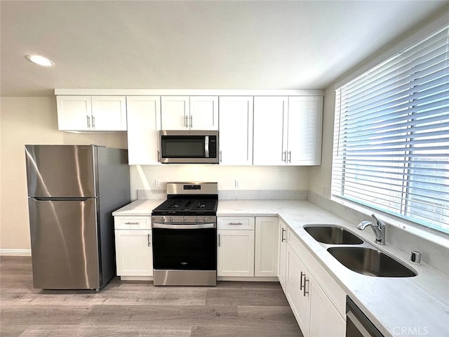 kitchen featuring white cabinetry, sink, appliances with stainless steel finishes, and light hardwood / wood-style flooring