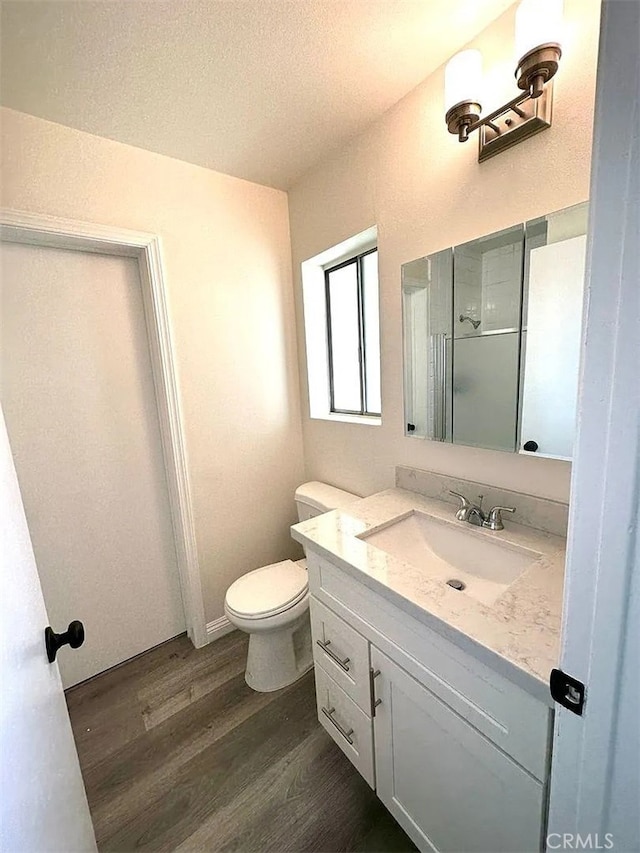 bathroom with hardwood / wood-style floors, vanity, toilet, and a textured ceiling