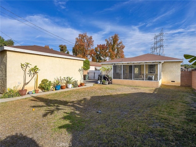 rear view of house with a lawn and a sunroom