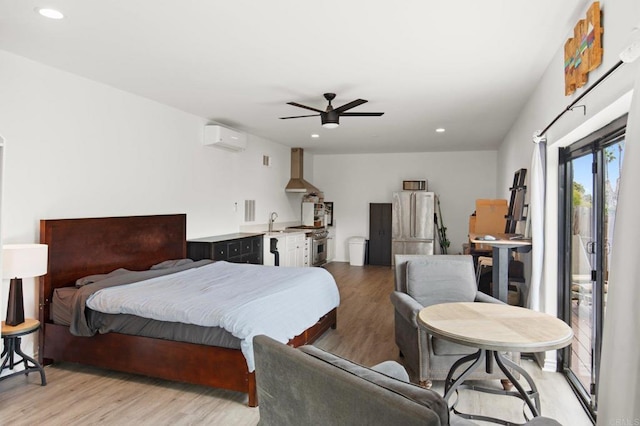 bedroom with ceiling fan, a wall mounted AC, sink, and light hardwood / wood-style floors