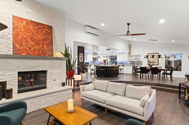 living room featuring a wall mounted AC, ceiling fan, a fireplace, wood-type flooring, and vaulted ceiling