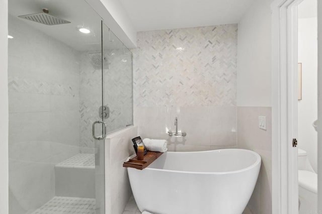 bathroom featuring plus walk in shower, toilet, and tile walls