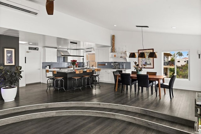 dining space featuring lofted ceiling, ceiling fan, dark hardwood / wood-style floors, sink, and a wall mounted air conditioner