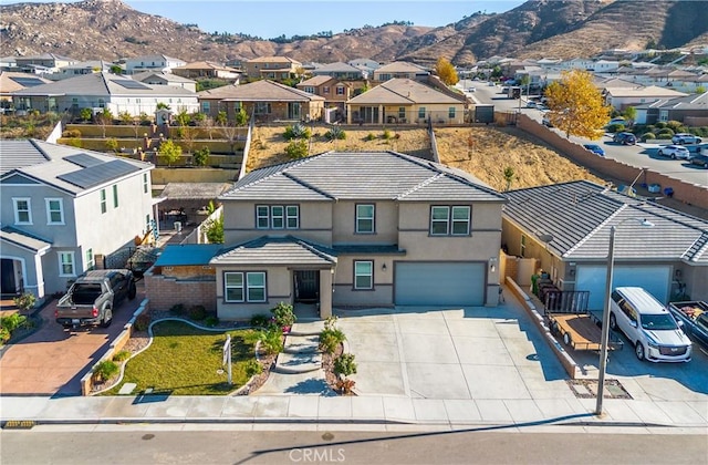 traditional-style house with stucco siding, a residential view, a garage, and a mountain view