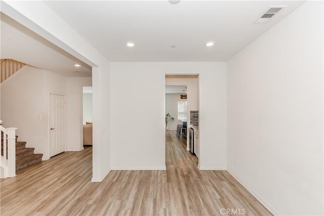 spare room featuring light wood-type flooring, visible vents, recessed lighting, and stairway