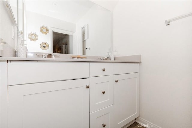 bathroom featuring double vanity, baseboards, and a sink