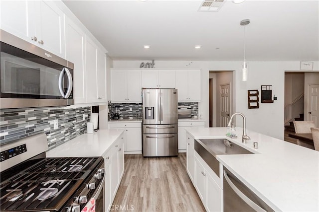 kitchen with visible vents, a sink, appliances with stainless steel finishes, light wood finished floors, and light countertops