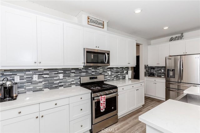 kitchen with light wood-style flooring, white cabinetry, stainless steel appliances, light countertops, and decorative backsplash