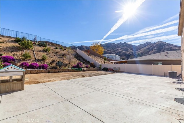 view of patio featuring a mountain view, central AC, and fence