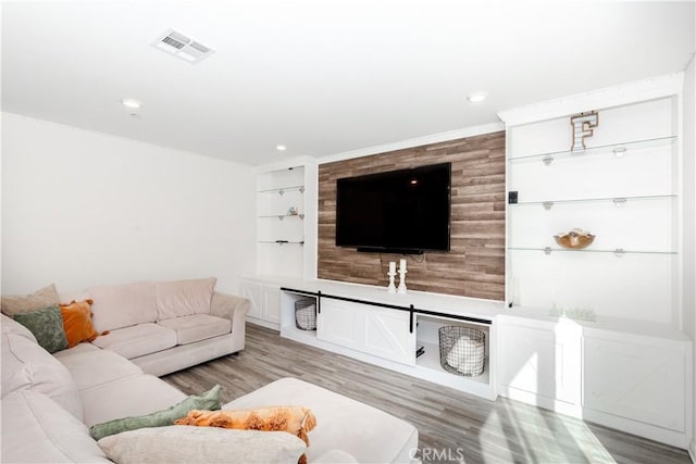 living room featuring light wood-style flooring, built in features, recessed lighting, and visible vents