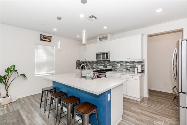 kitchen featuring a breakfast bar area, visible vents, a sink, decorative backsplash, and appliances with stainless steel finishes