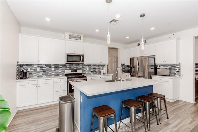 kitchen featuring visible vents, a sink, stainless steel appliances, a kitchen breakfast bar, and light wood-type flooring