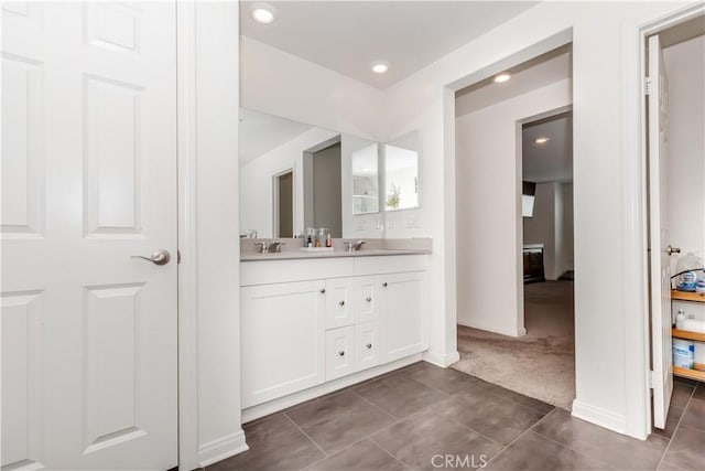 full bath featuring double vanity, baseboards, a sink, and tile patterned flooring