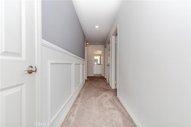 corridor featuring baseboards and light colored carpet