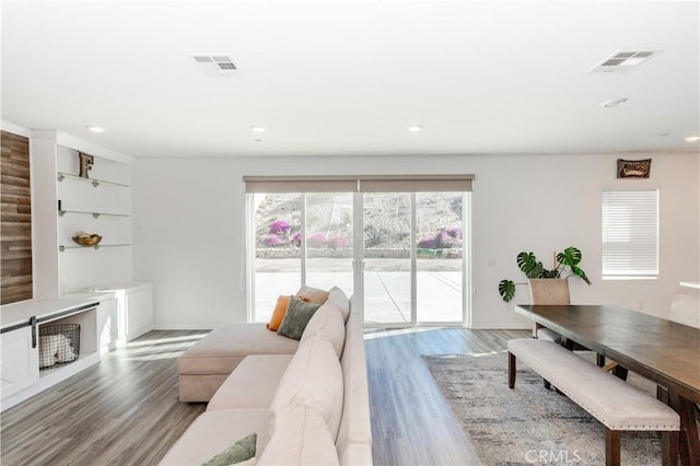 living room with visible vents, recessed lighting, and wood finished floors