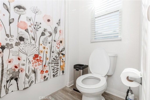 bathroom featuring a shower with curtain, toilet, wood finished floors, and baseboards