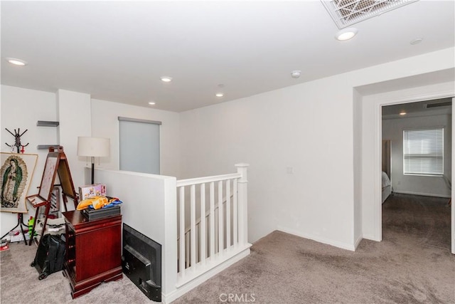 hallway with carpet, visible vents, baseboards, recessed lighting, and an upstairs landing