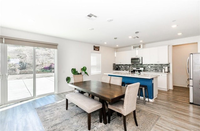 dining area featuring light wood-style flooring, recessed lighting, visible vents, and baseboards