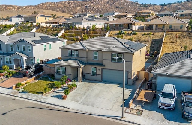 view of front of property with driveway, an attached garage, a residential view, stucco siding, and a mountain view