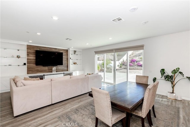 dining space with visible vents, recessed lighting, built in features, and wood finished floors